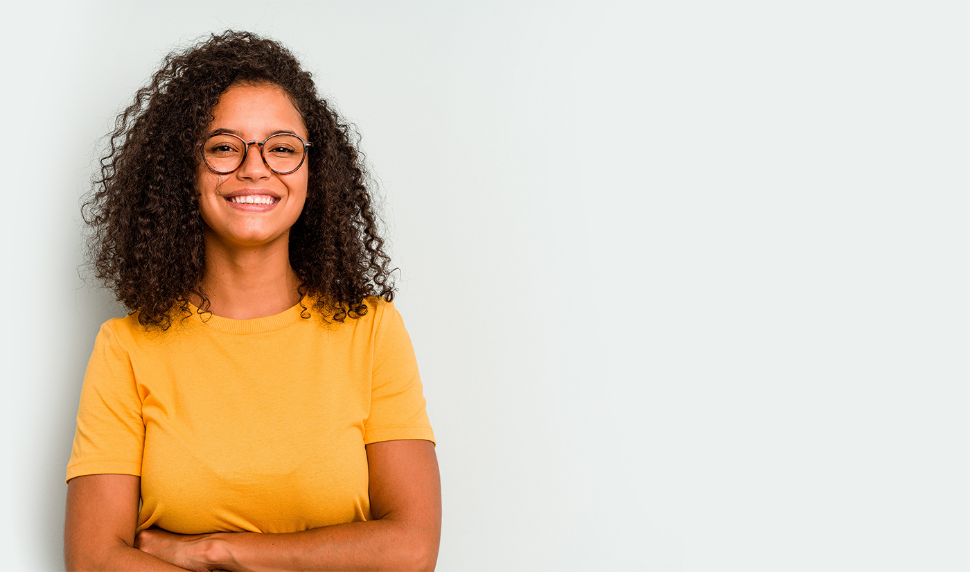 Mulher sorrindo, usando óculos e uma blusa amarela